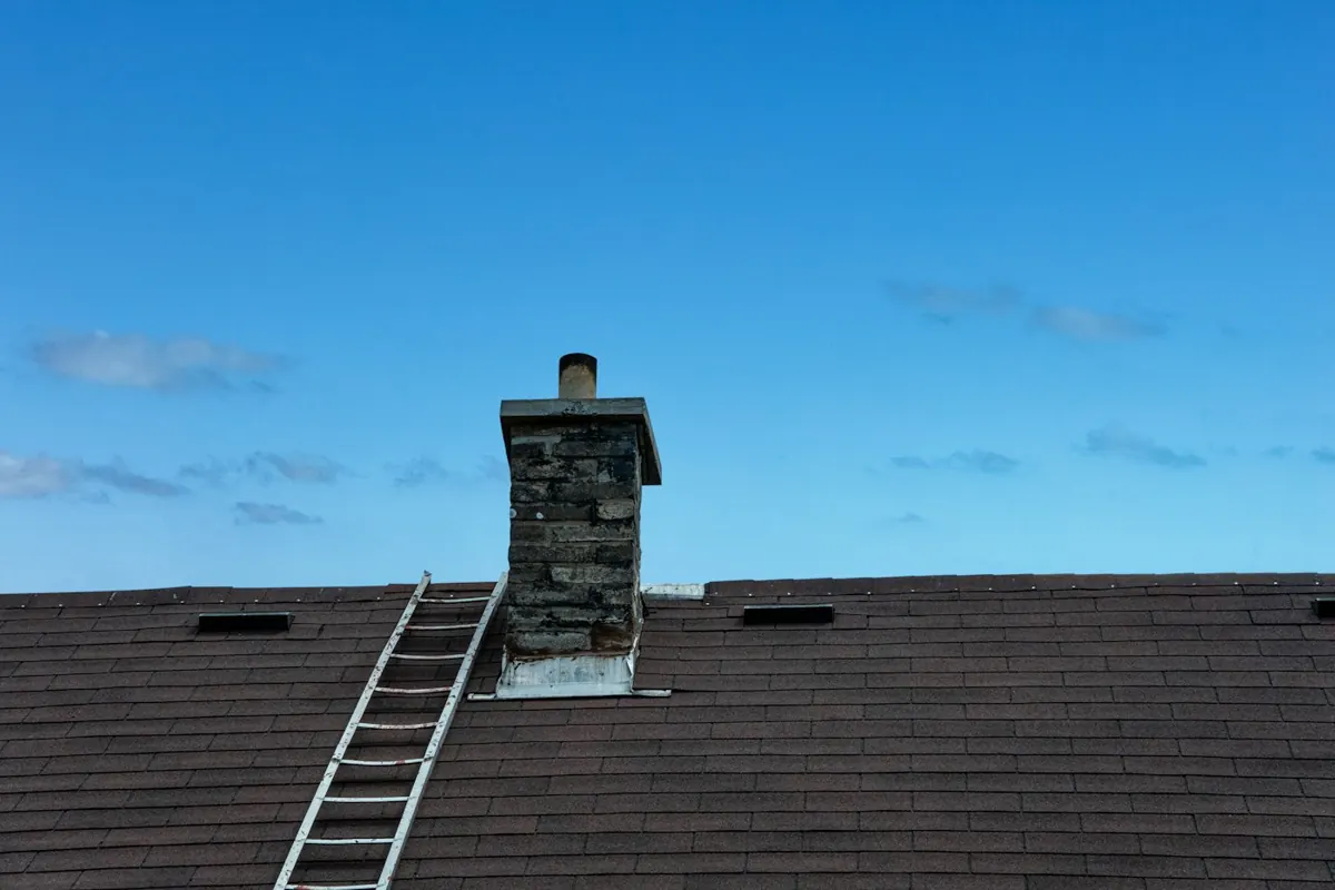 Ladder against a brick chimney on a roof